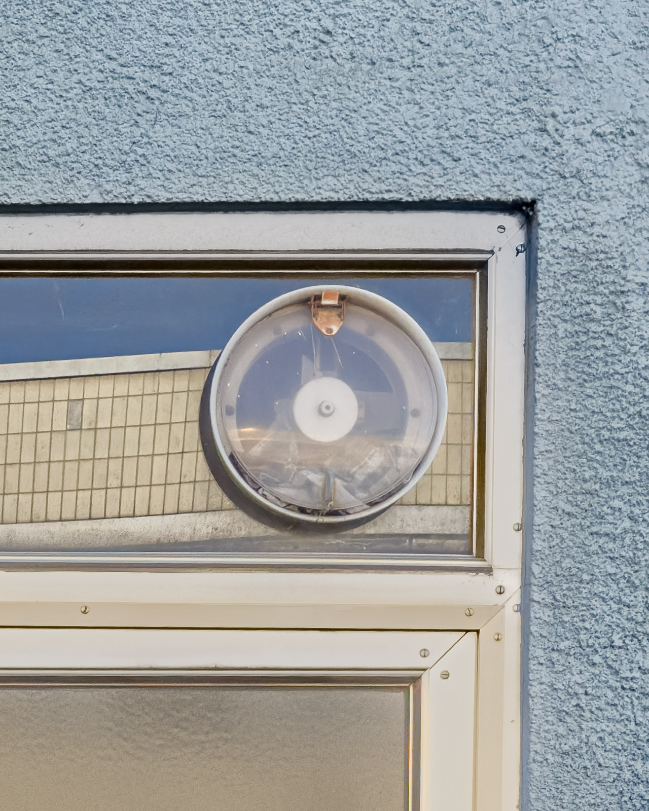 Former storefront entrance in Zeltweg, Austria, with a ventilation fan above the door and a closed display