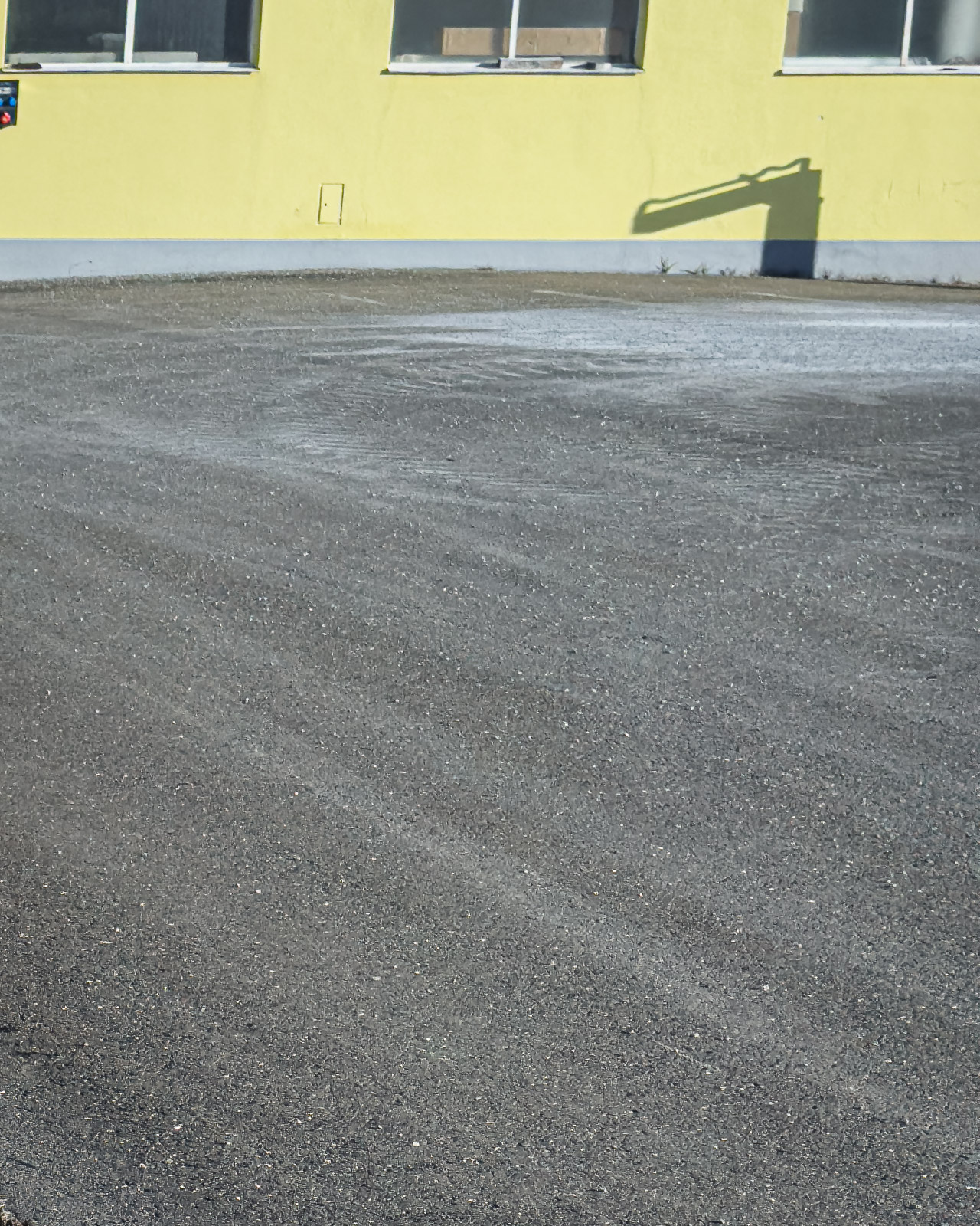Empty paved surface beside an industrial building in Zeltweg.